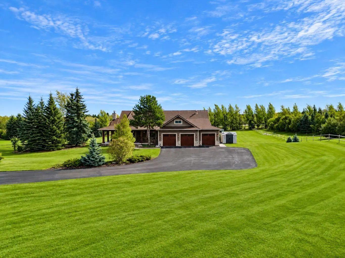 A country home on a large, treed acreage with a long paved driveway