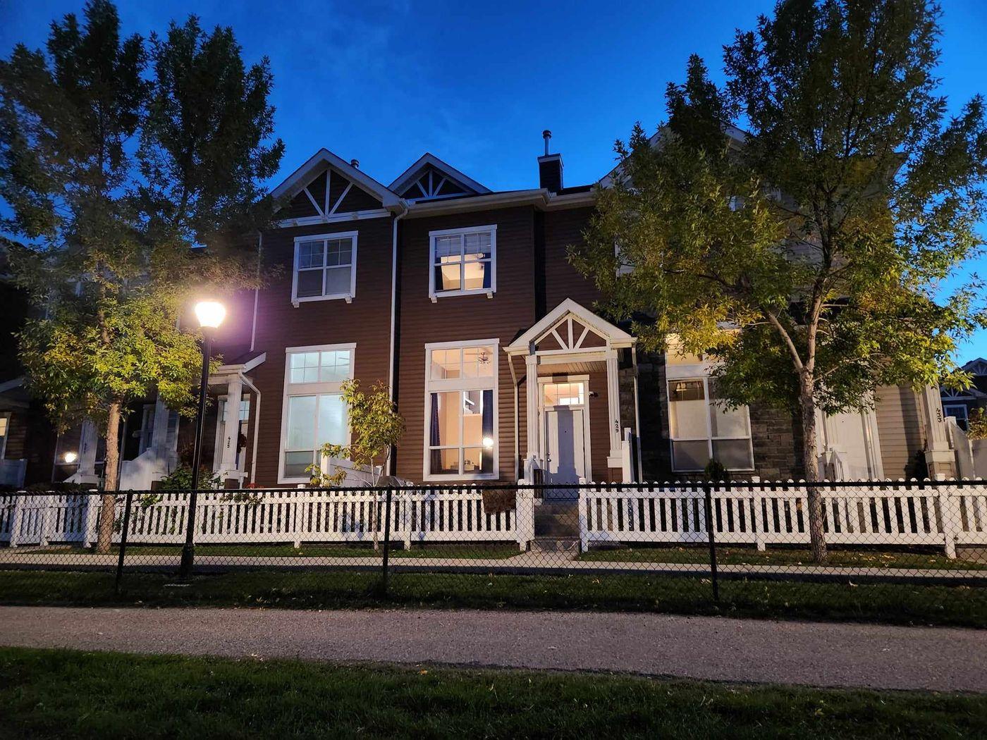 Townhome with white picket fence at dusk in Inverness, McKenzie Towne