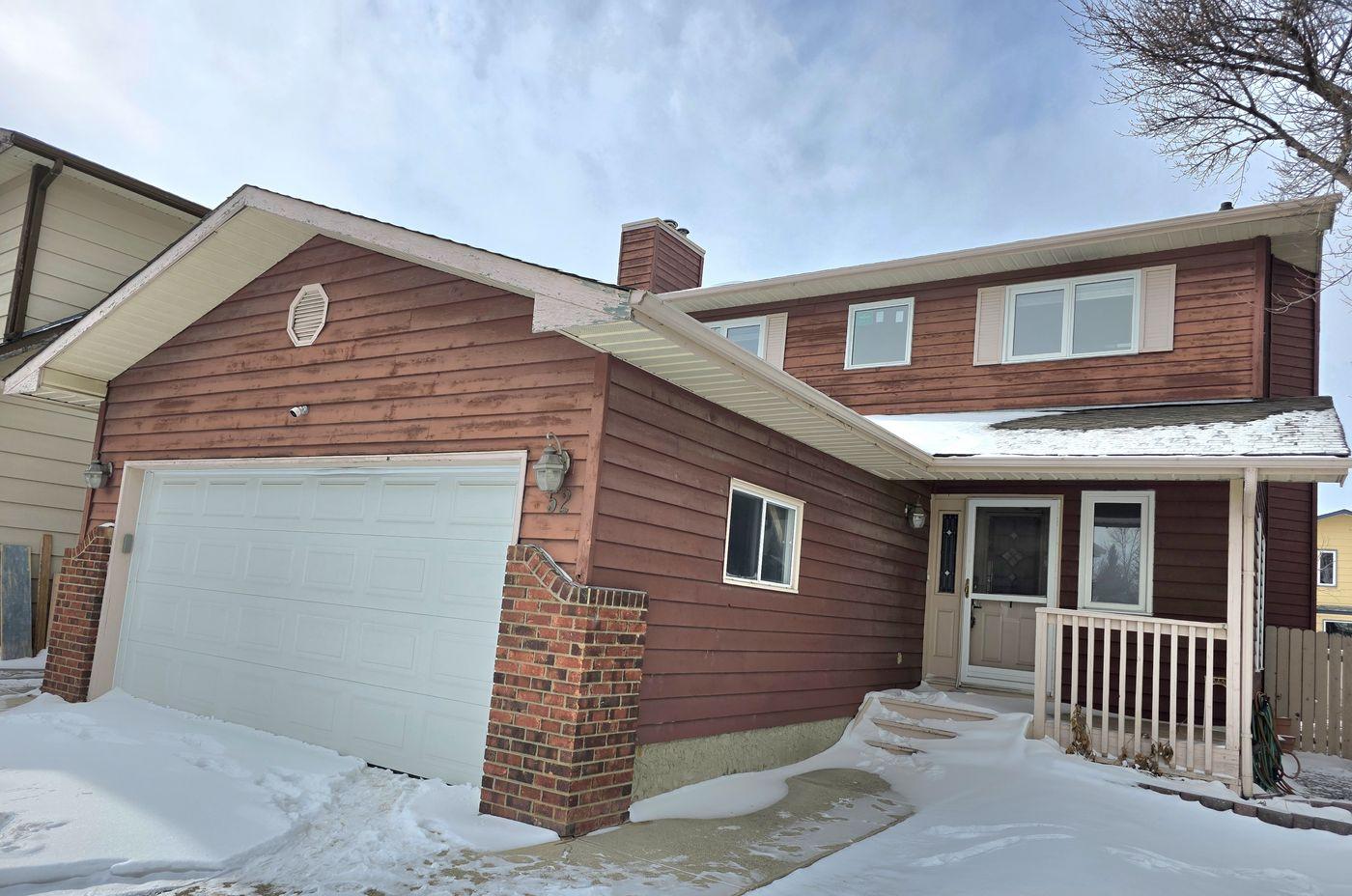 Two-storey home with red cedar siding in winter in Sundance